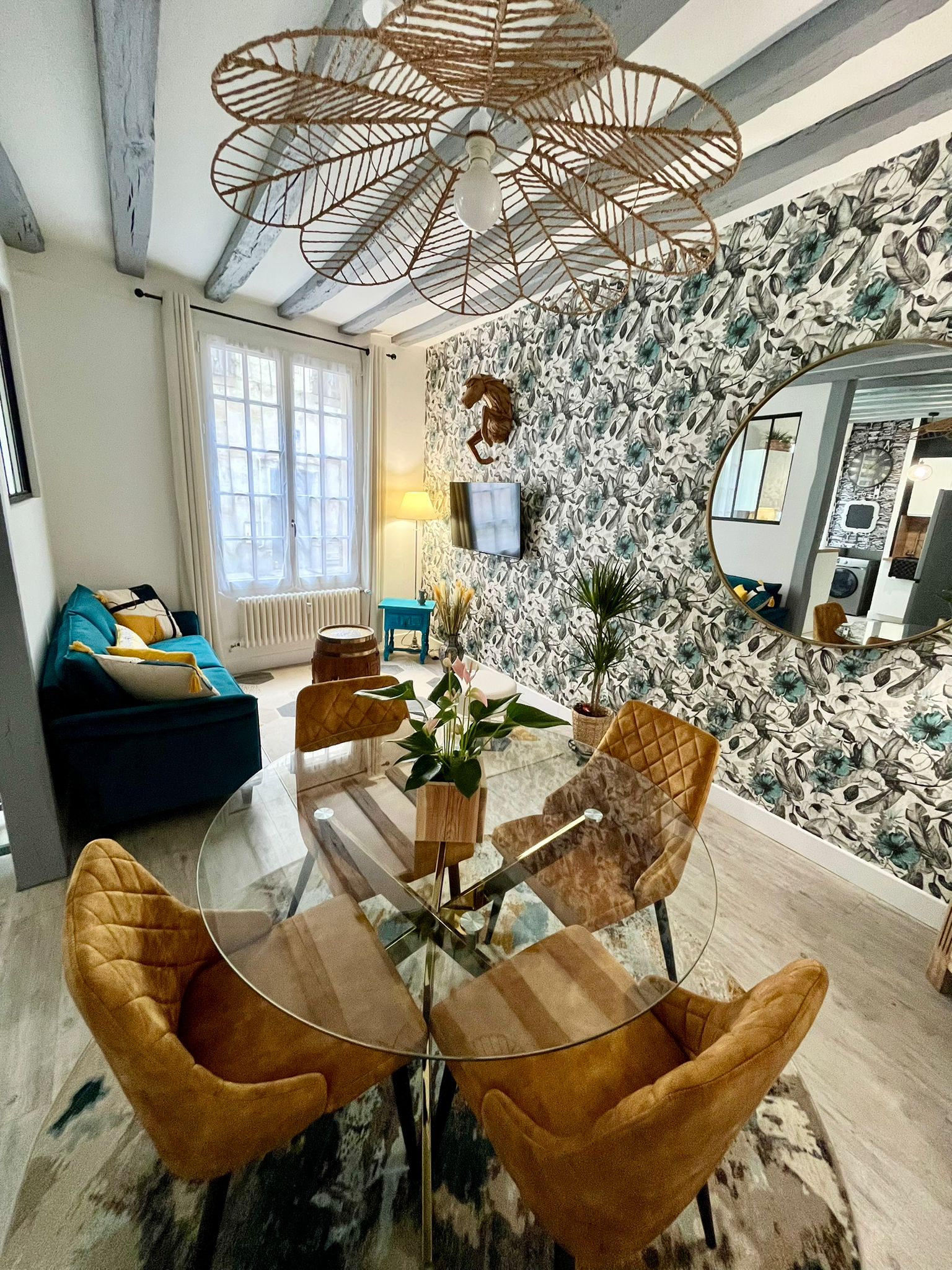Salon lumineux avec table en verre et fauteuils en velours doré.