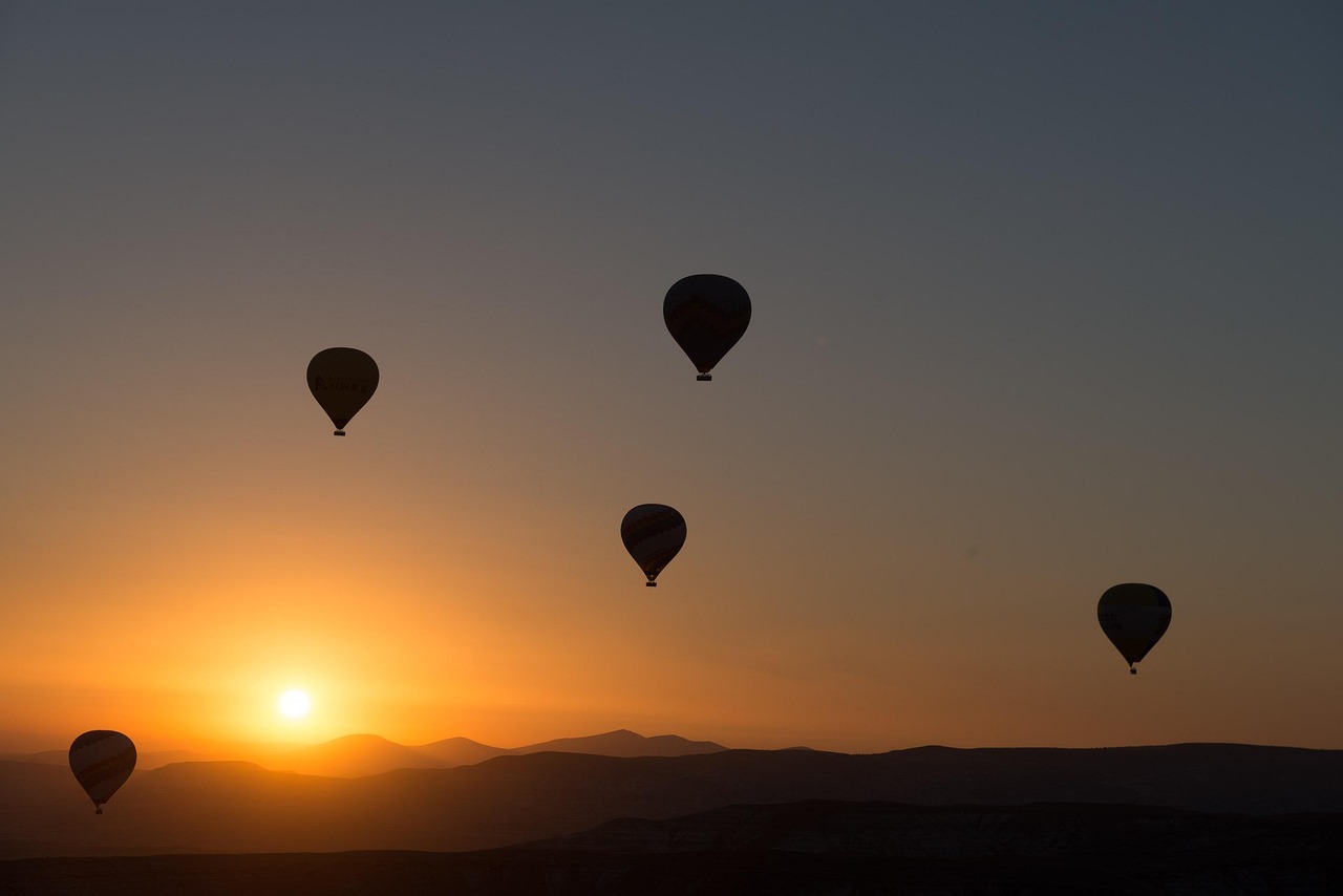 Montgolfières devant un soleil couchant.
